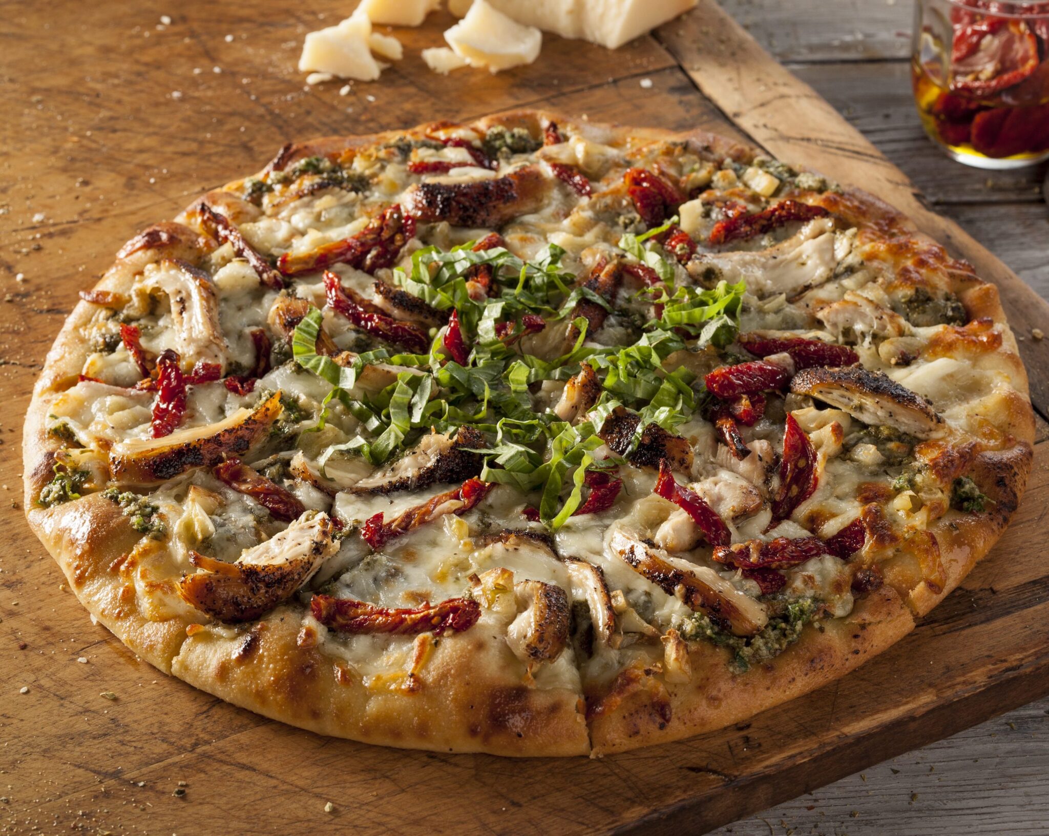 Roasted chicken, roasted red pepper, basil and cheese topped pizza.